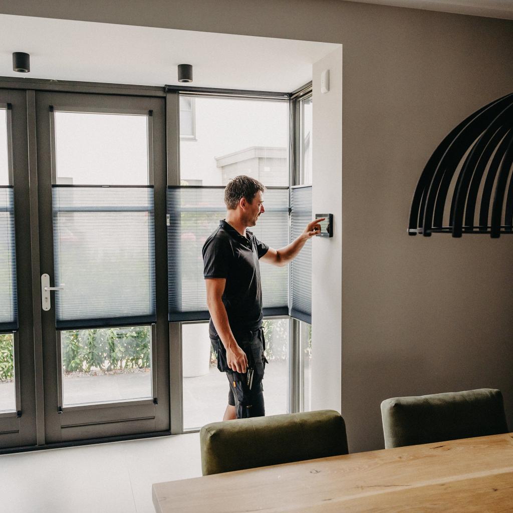 Man die in een woonkamer op een touchscreen aan de muur drukt.